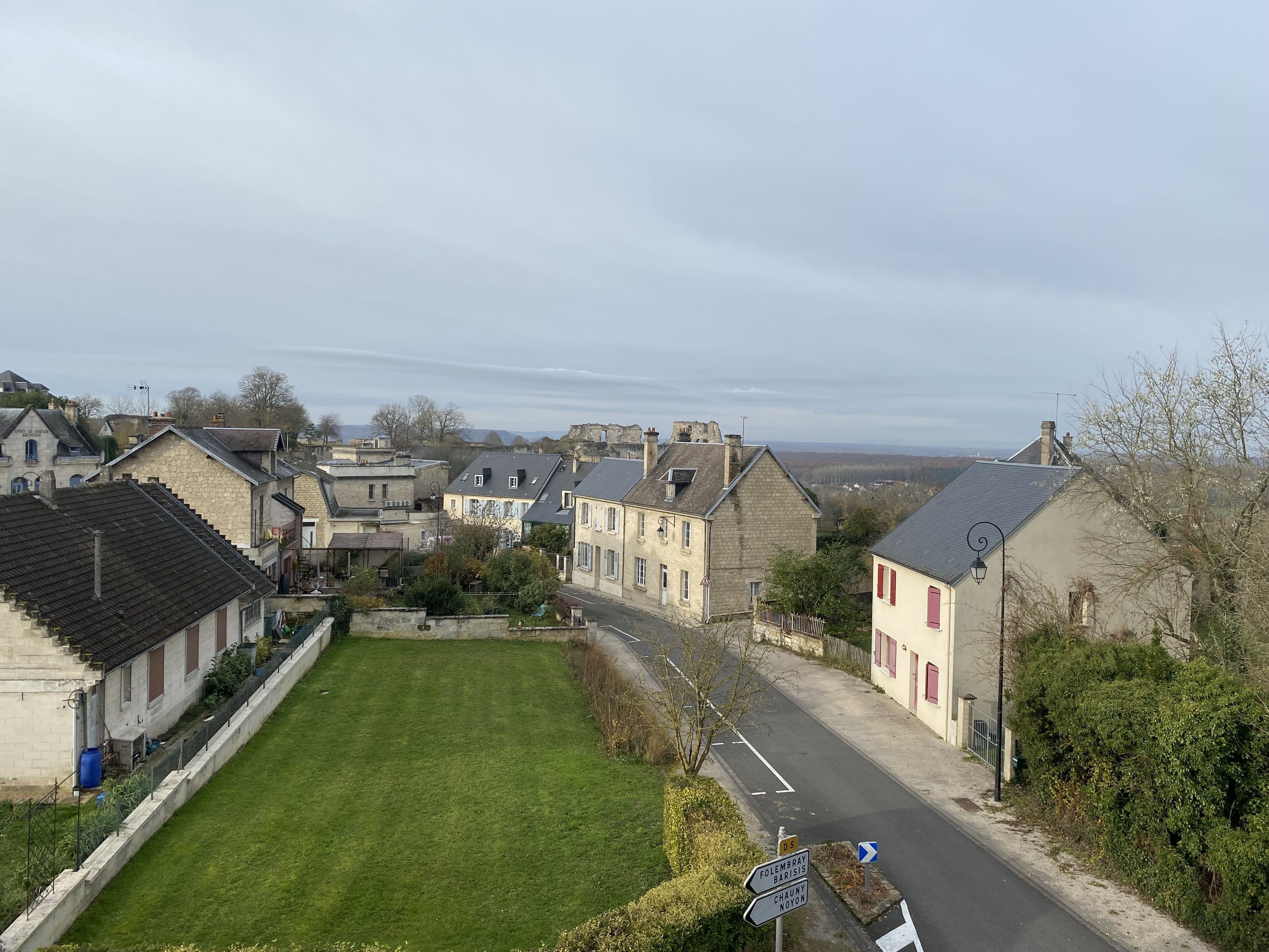 A residential area with stone buildings, a grassy lawn, and a road with directional signs.