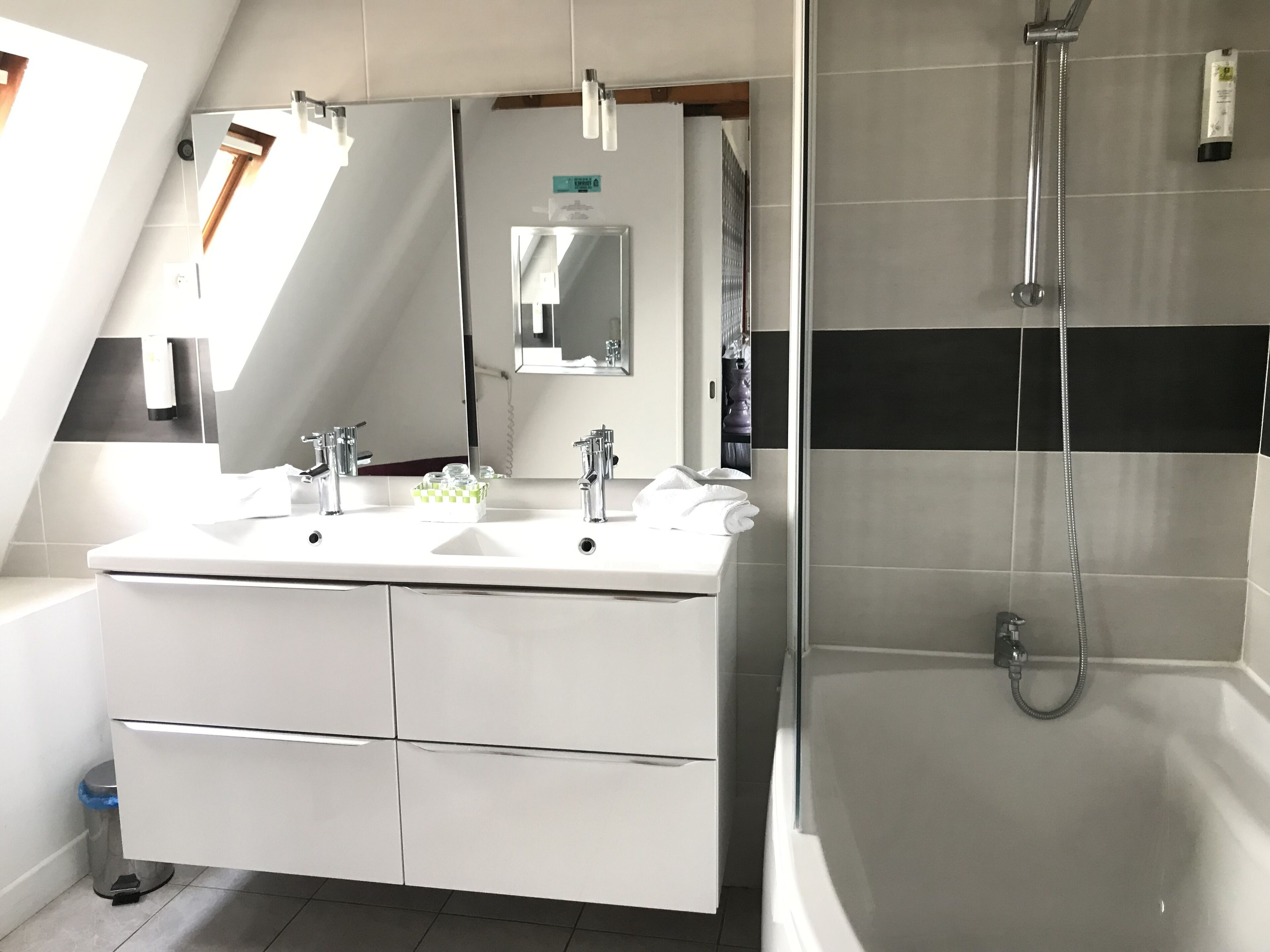 Une salle de bain moderne dotée d’un meuble-lavabo à deux vasques, d’un grand miroir et d’une douche à l’italienne.