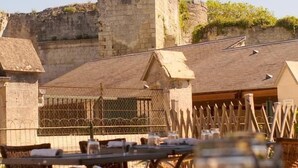 A view of a stone wall and a building with a small tower, likely part of a historical site. - Hôtel Belle Vue (Coucy-le-Chateau-Auffrique)