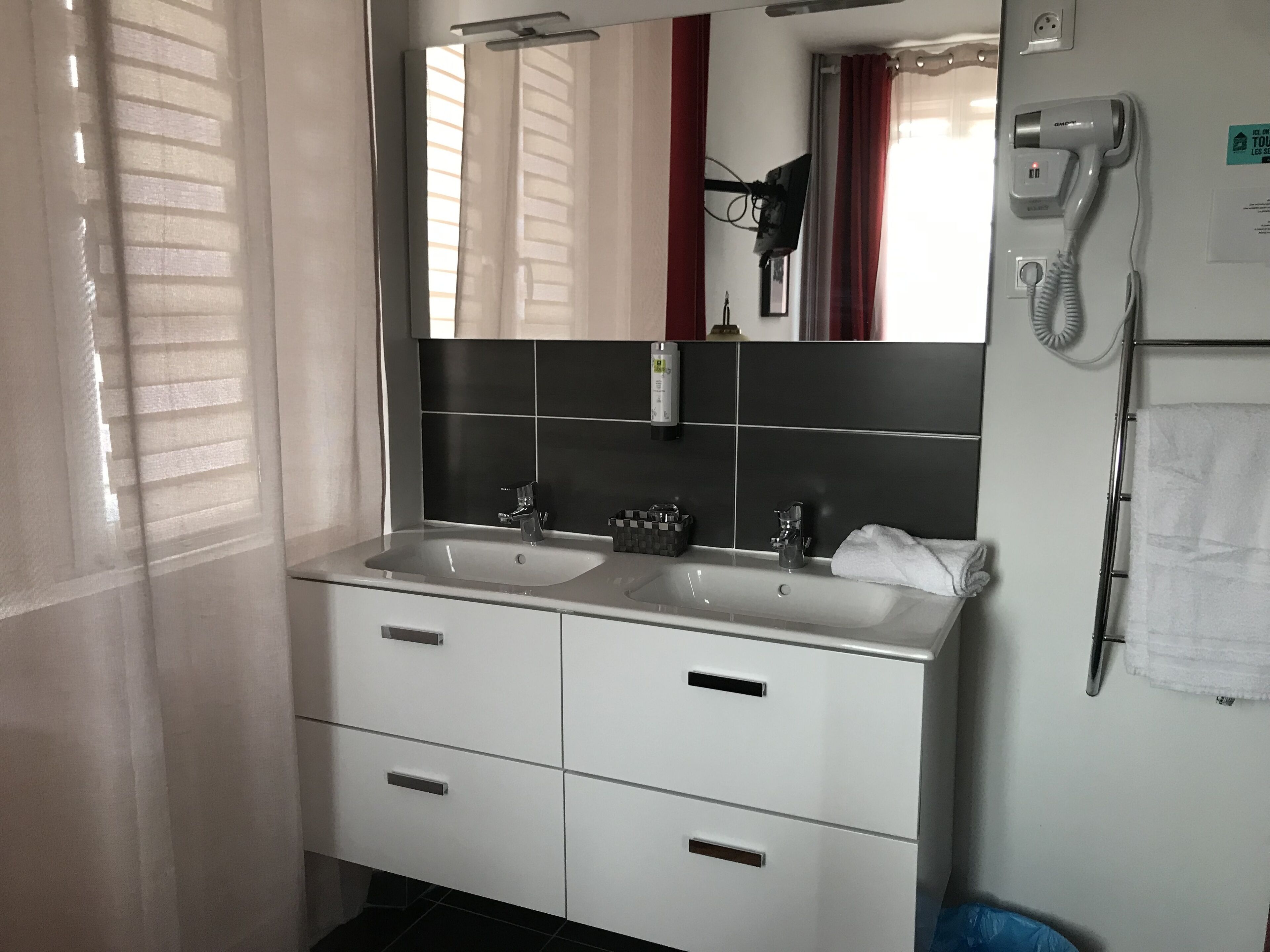 A bathroom with two sinks, a mirror, a hairdryer, and a towel rack.