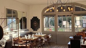 A dining area with tables and chairs, a large mirror, and a view through the windows. - Hôtel Belle Vue (Coucy-le-Chateau-Auffrique)