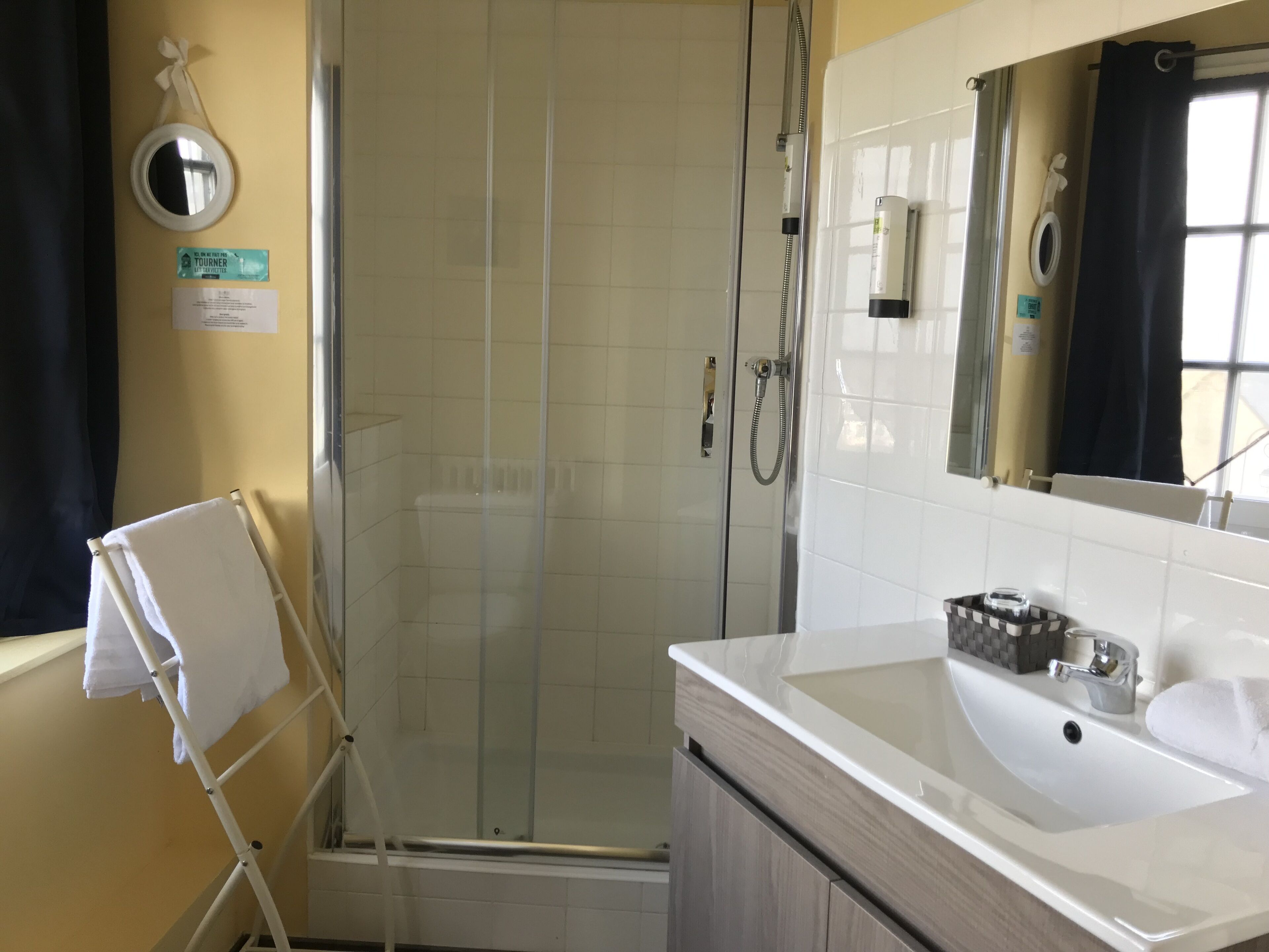 Een badkamer met een douche met glazen wand, een witte wastafel en een handdoekhouder.