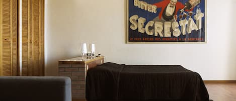 Une chambre d’hôtel avec un lit, une petite table avec une lampe et une affiche accrochée au mur.
