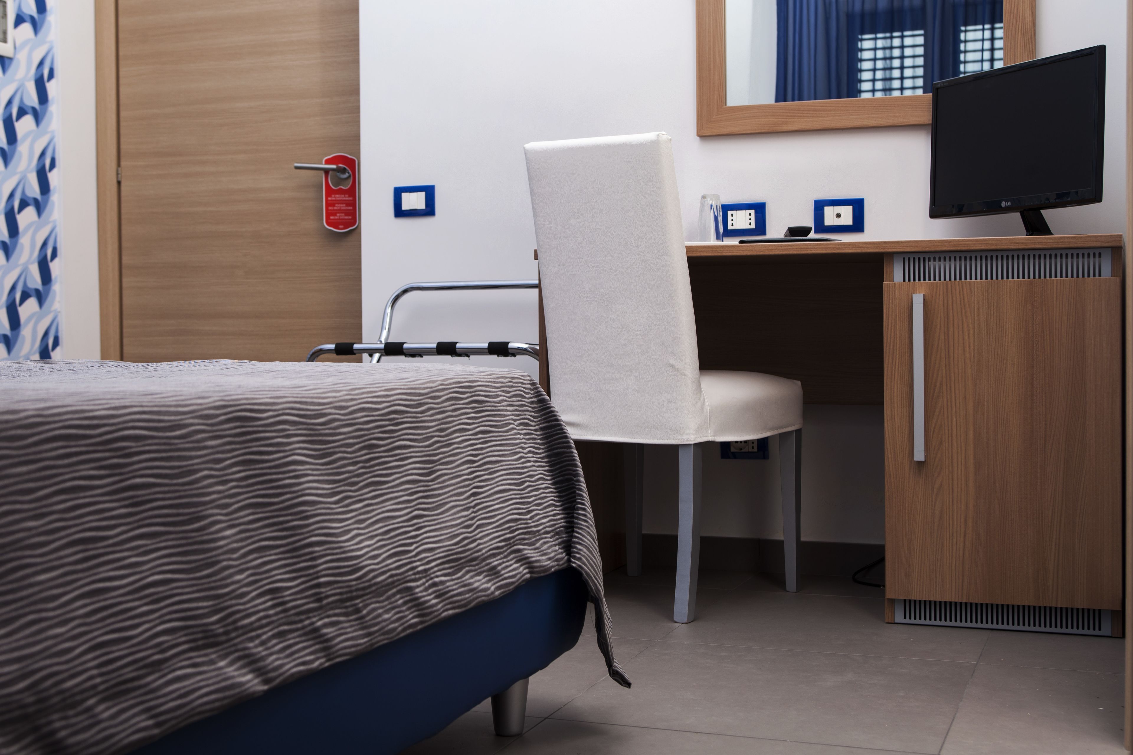Una habitación de hotel con cama, escritorio, silla, televisión y armario.