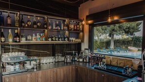 A bar area with shelves of liquor bottles, a coffee machine, and a view of a pool through a window. - B&B Villaseta (Agrigento)