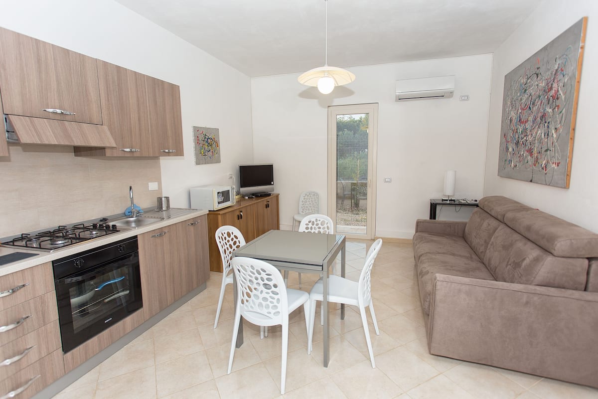 A modern kitchen with a dining area, a sofa, and a TV.