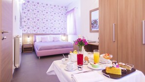 A hotel room with a bed, a dining table with breakfast items, and a bathroom with a shower. - B&B Villaseta (Agrigento)