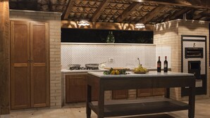 A kitchen with a wooden table, a brick backsplash, and a built-in oven. - B&B Villaseta (Agrigento)
