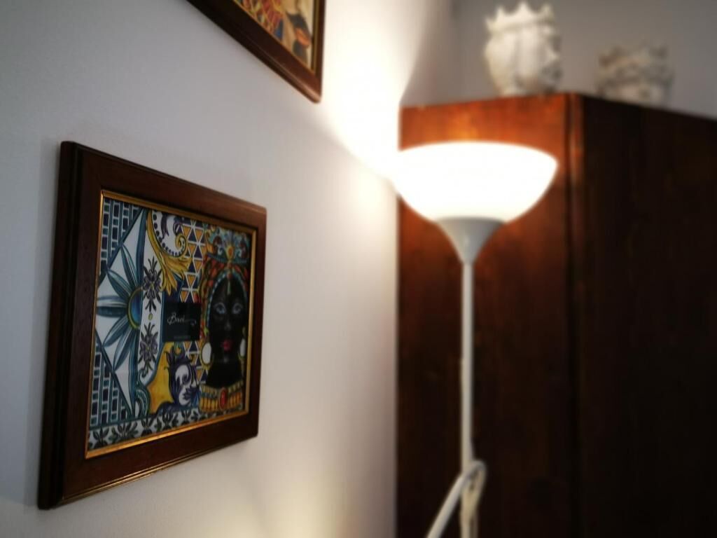 Un mur orné d’un tableau encadré et une lampe de sol blanche.