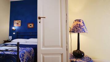 A room with a bed, a bedside table with a lamp, and a door.