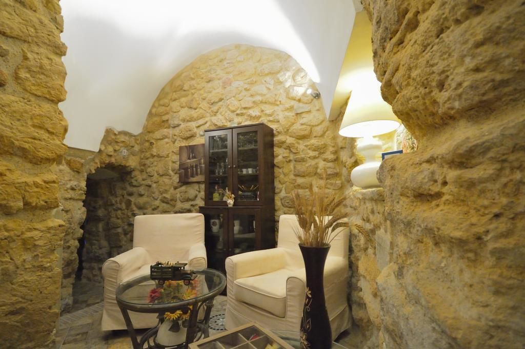 A cozy room with stone walls, a wooden cabinet, two white armchairs, and a small table with a vase.