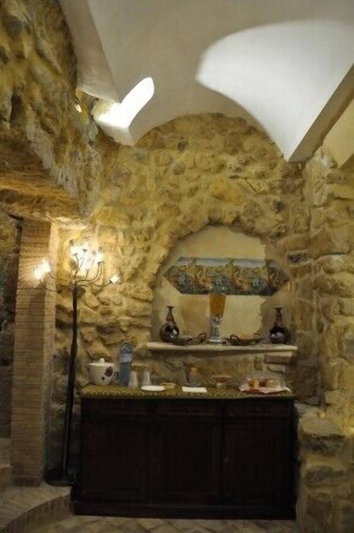 A stone-walled room with a built-in bench and a chandelier.