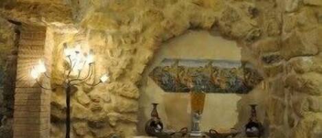 A stone-walled room with a built-in bench and a chandelier.