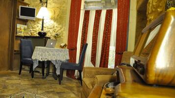 Una habitación acogedora con una mesa de comedor, sillas, una computadora portátil, un televisor y un sofá.