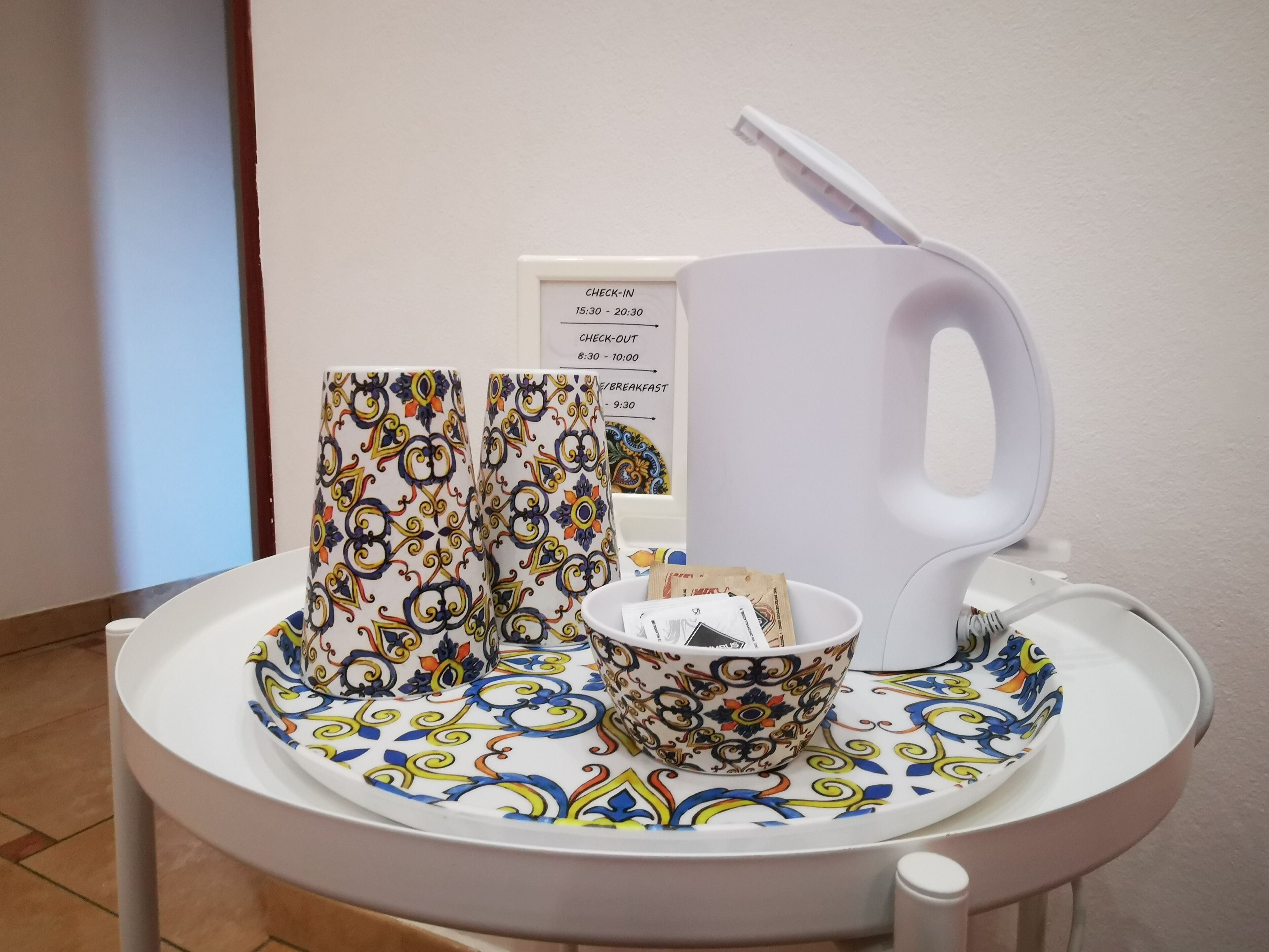 A table with a tray, a cup, a bowl, and a sign with check-in and check-out times.