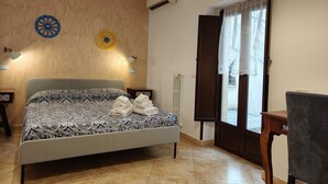 Un dormitori amb un llit, aire condicionat fixat a la paret, una finestra amb cortines i una taula petita.