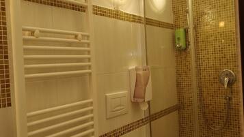 A bathroom with a glass shower enclosure, a toilet, and a towel rack.