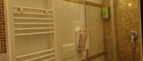 A bathroom with a glass shower enclosure, a toilet, and a towel rack.