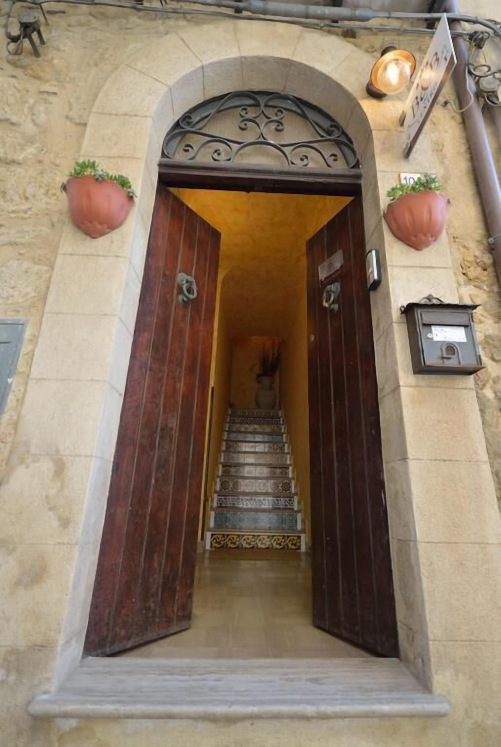 Entrada de un edificio de piedra con una puerta de madera y una escalera que lleva al interior.