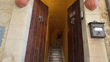 Entrada de un edificio de piedra con una puerta de madera y una escalera que lleva al interior.