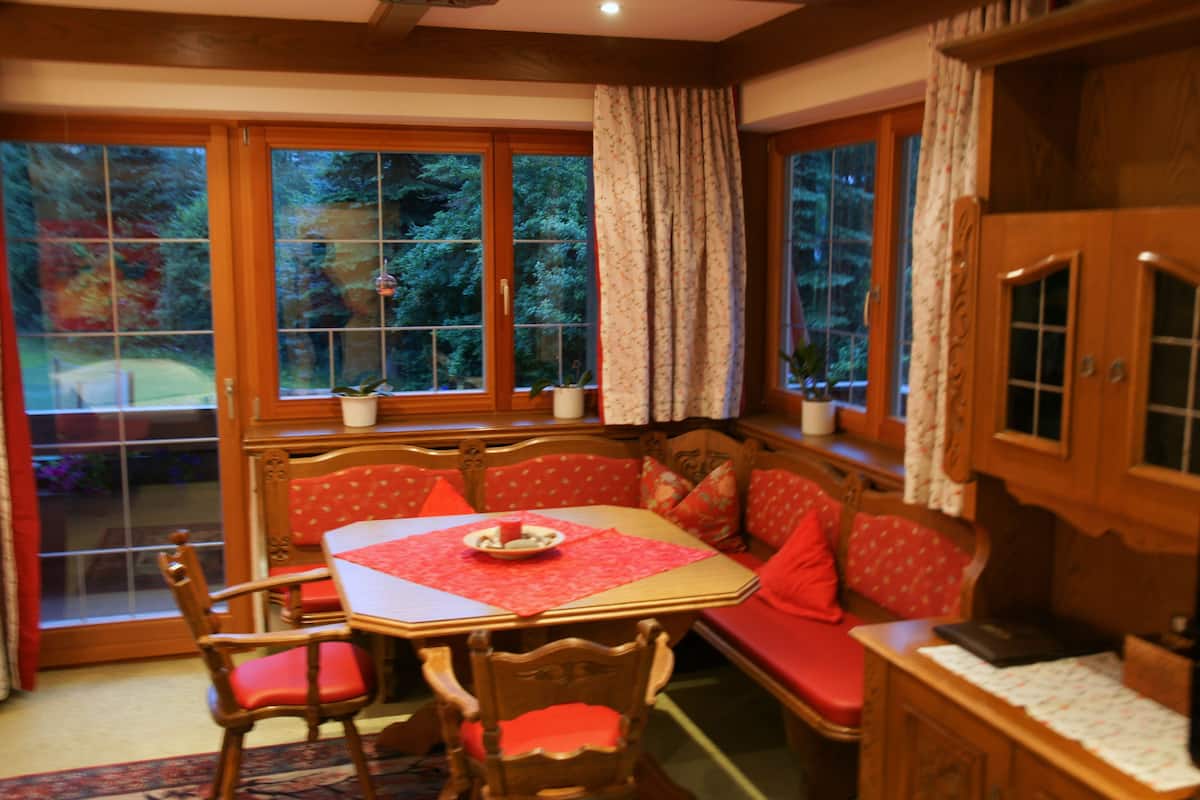 A dining area with a wooden table, red upholstered bench, and chairs.
