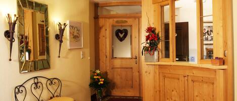 Zona de recepción con un mostrador de madera, un banco, un espejo y una pared decorada con un corazón.