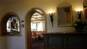 A hallway with a stained glass window, a wooden bench, a table with chairs, and a mirror on the wall. - Pension Sportalm (Soelden)