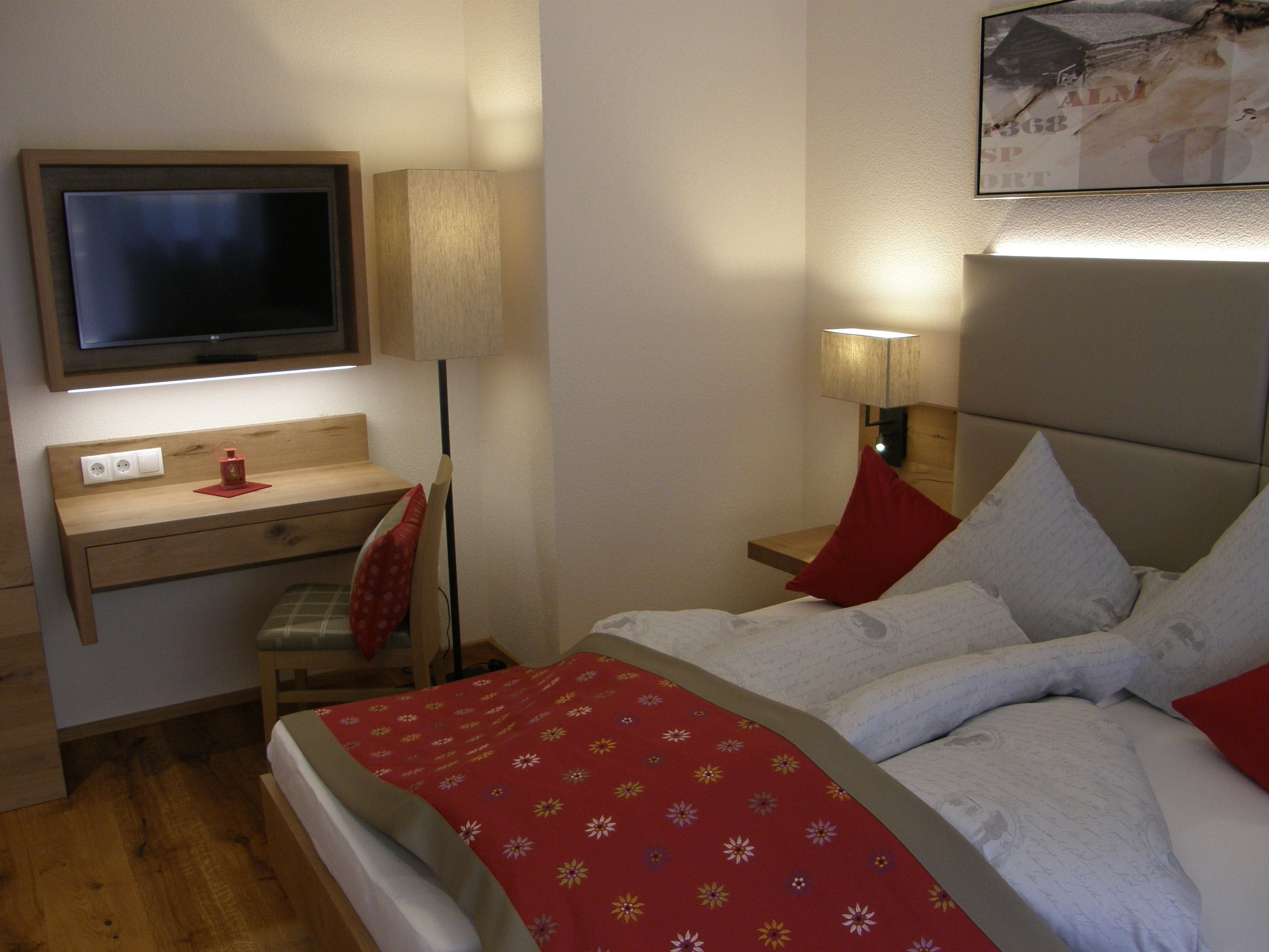 Une chambre d’hôtel avec un lit, un bureau avec un ordinateur, une télévision et une lampe.