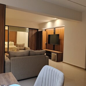 A modern living room with a sofa, a TV mounted on the wall, and a sliding door leading to a bedroom. - Alexander the Great Hotel - Alexotel (Alexandria)