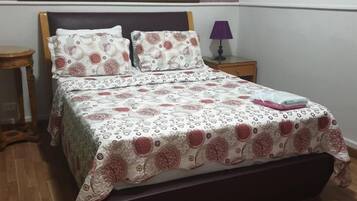 A bedroom with a bed, a nightstand, a lamp, and a wall tapestry.