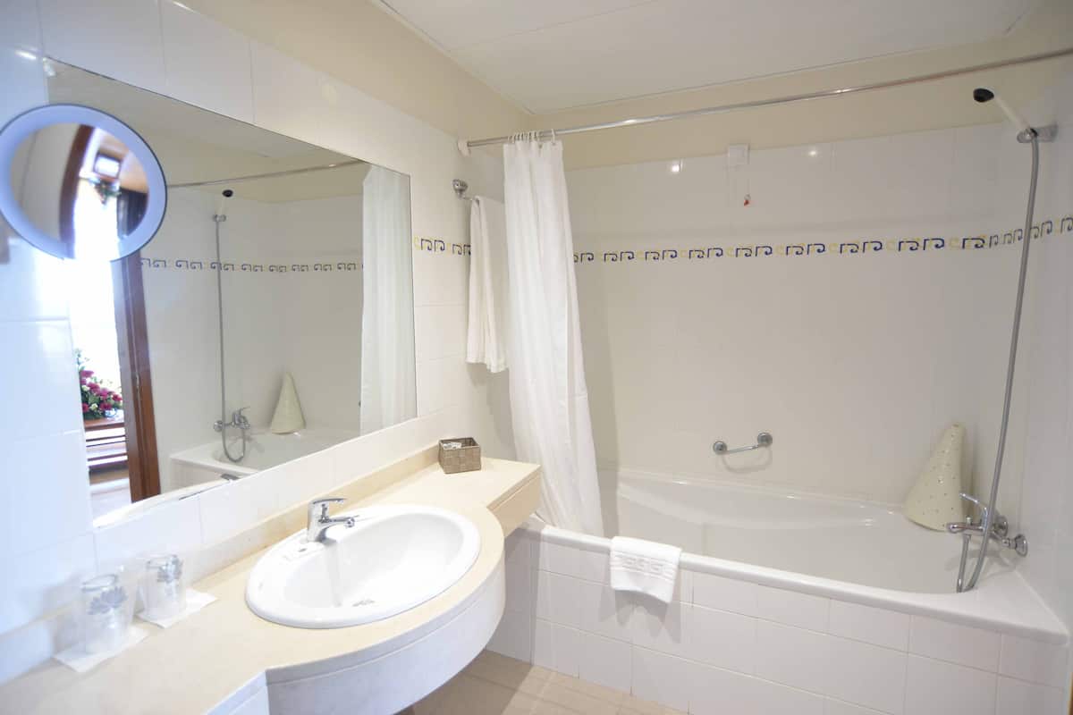 A bathroom with a sink, mirror, and bathtub.