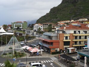 A coastal town with a mix of residential and commercial buildings, a pedestrian crossing, and a parking area with cars. - Hotel Salgueiro (Porto Moniz)