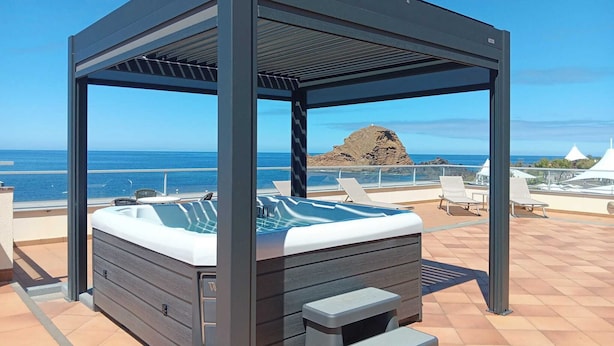 A rooftop pool area with a hot tub, lounge chairs, and a pergola structure. - Hotel Salgueiro (Porto Moniz)
