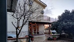 Um pátio pavimentado, uma árvore, um veado decorativo e um edifício com varanda.
