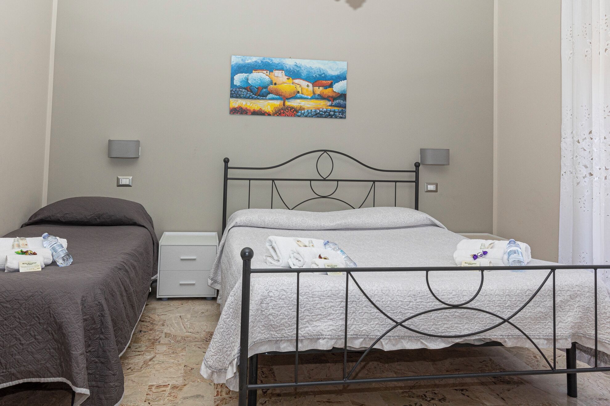 Un dormitorio con dos camas, un cuadro en la pared y una mesita de noche con lámpara.