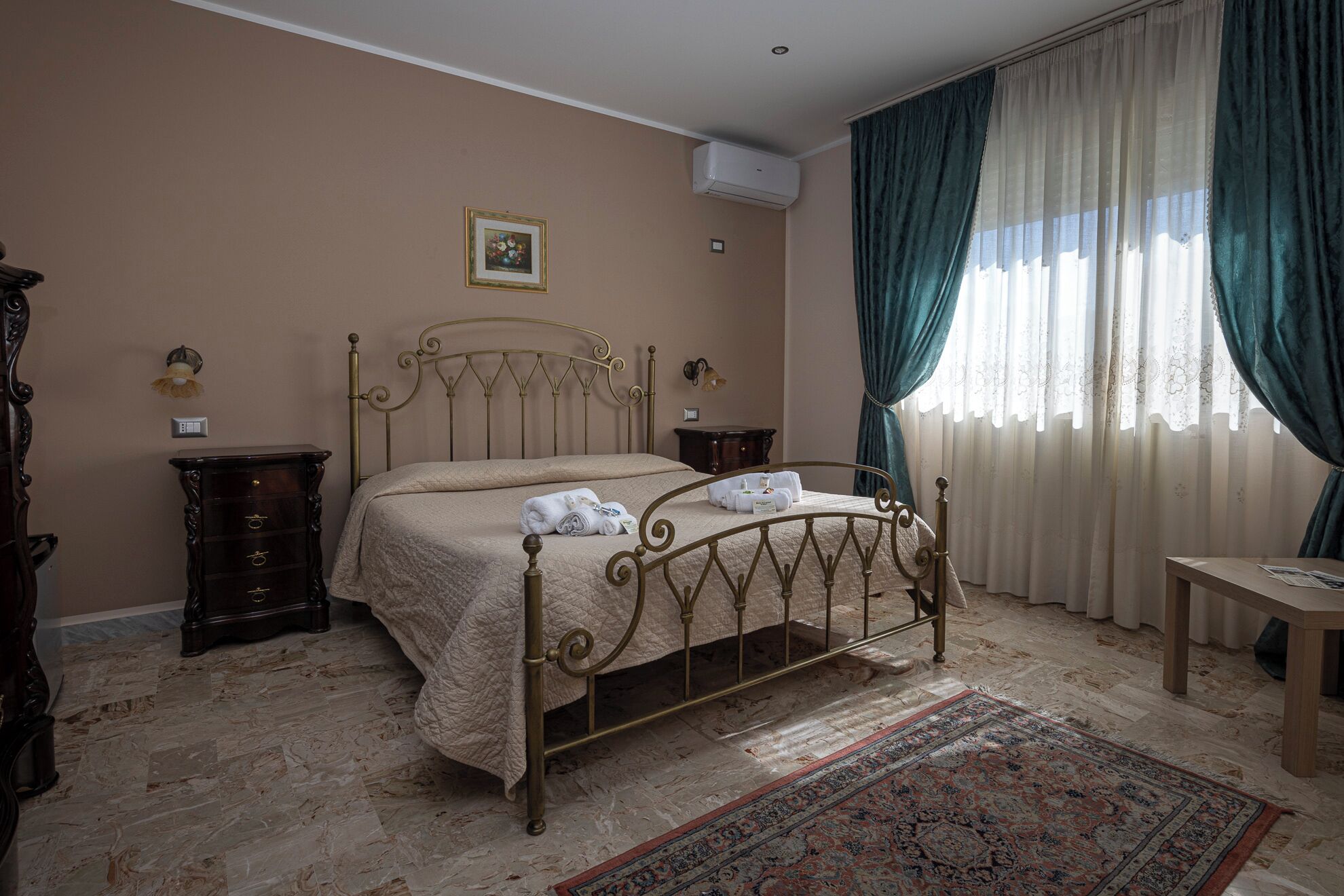 A bedroom with a bed, a nightstand, a dresser, a rug, and a window with curtains.
