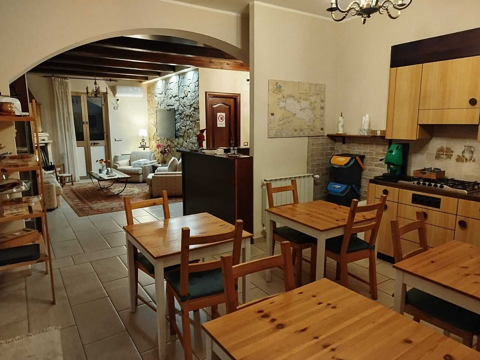 Un coin repas chaleureux avec des tables et des chaises en bois, une cuisine équipée d’une cuisinière et de placards, et un salon avec un canapé et une cheminée.
