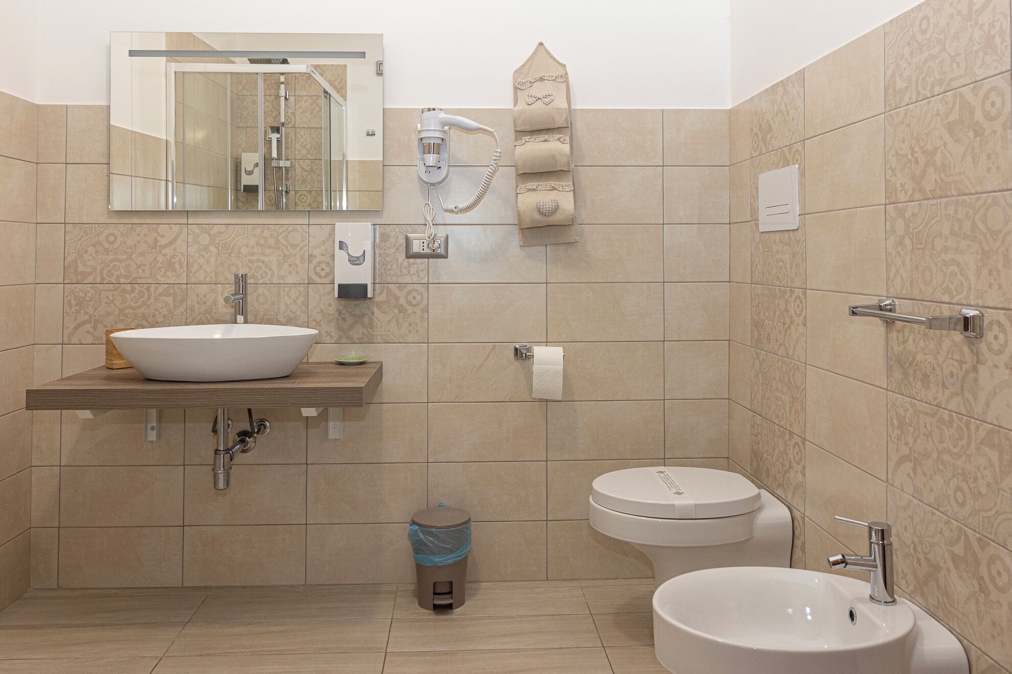 Une salle de bain avec un grand lavabo, des toilettes, un bidet et un miroir.