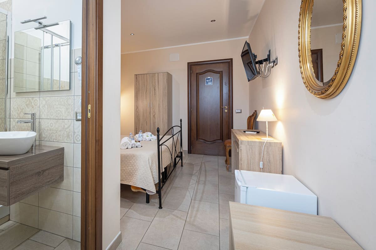 A hotel bathroom with a sink, mirror, towel rack, and a door with a WiFi sign.