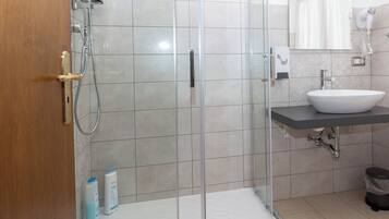 A modern bathroom with a glass shower enclosure, a white sink, and a mirror above it.