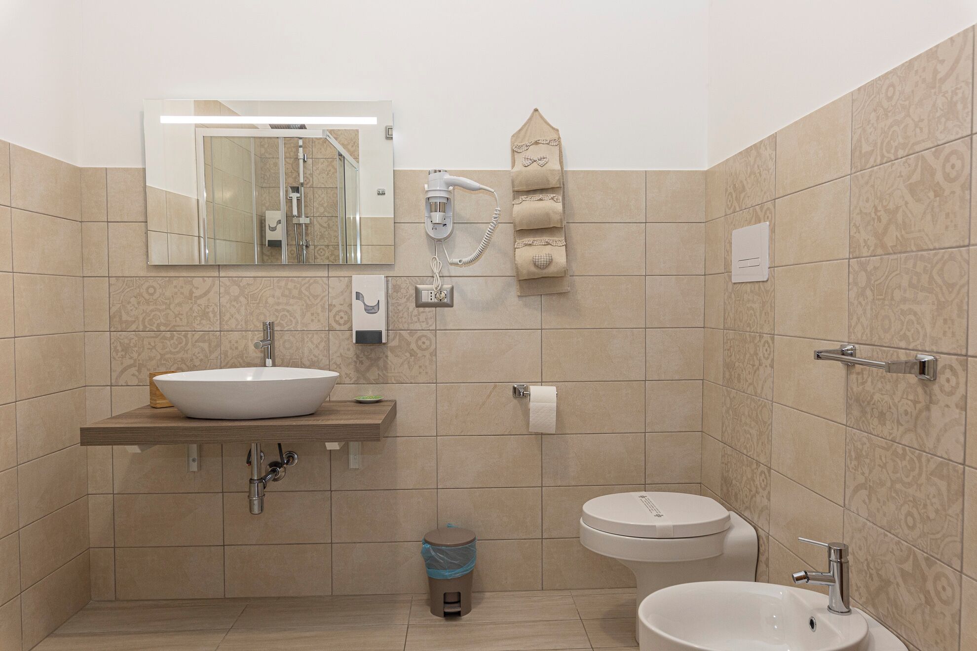 Ein modernes Badezimmer mit einem großen Spiegel, einem Waschbecken, einer Toilette und einem Bidet.