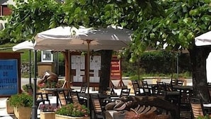 Outdoor seating with umbrellas, potted plants, and a signboard.