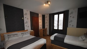 A bedroom with two beds, a desk, and a window.