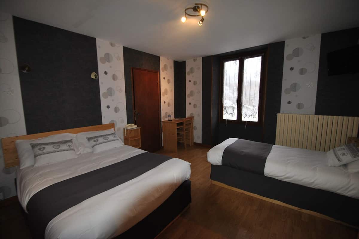 Une chambre avec deux lits, un bureau et une fenêtre.