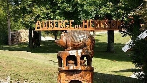 A wooden sign with a pig sculpture, reading "Auberge du Hêtre."