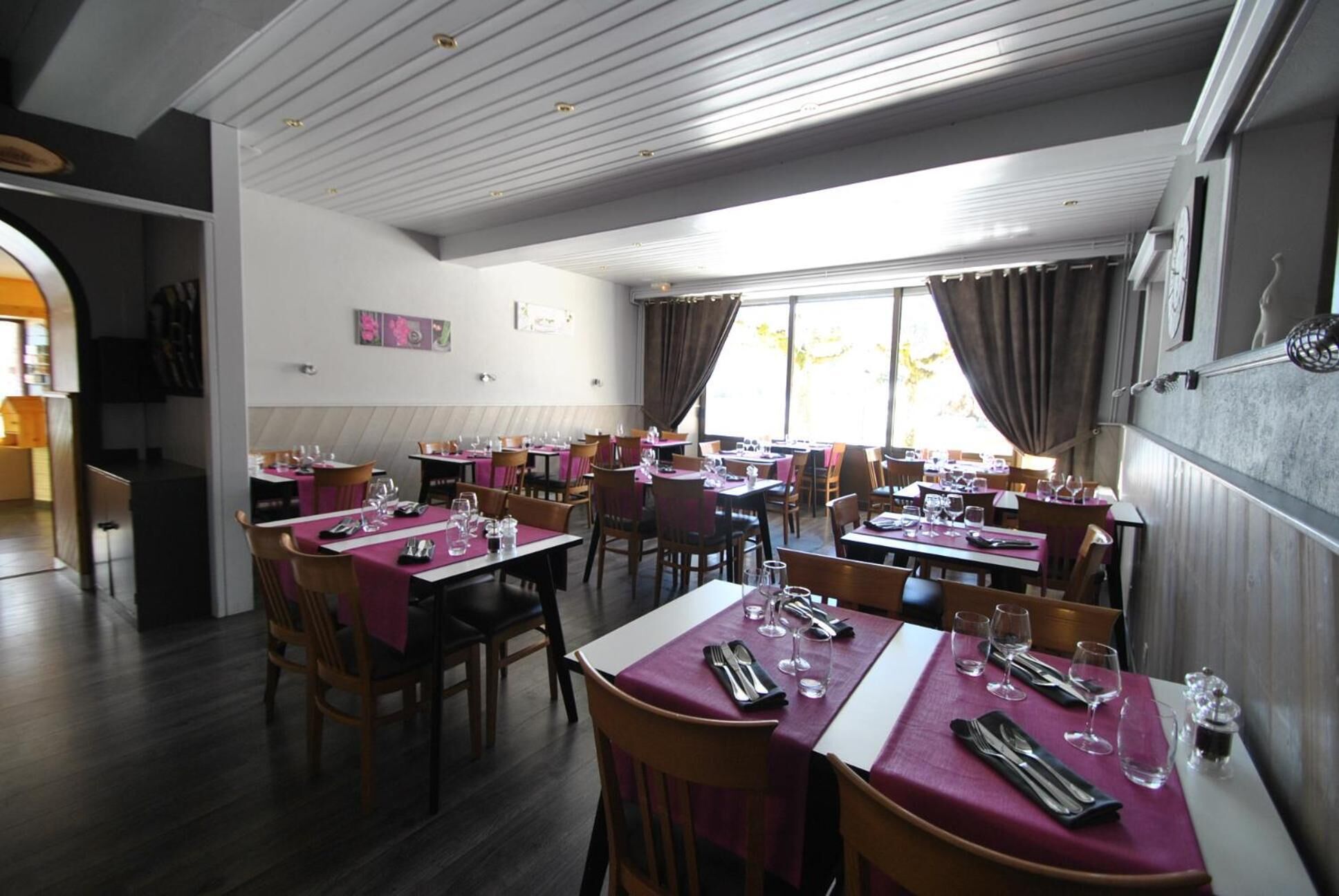 A restaurant with multiple tables and chairs, arranged in a spacious dining area with natural light from large windows.