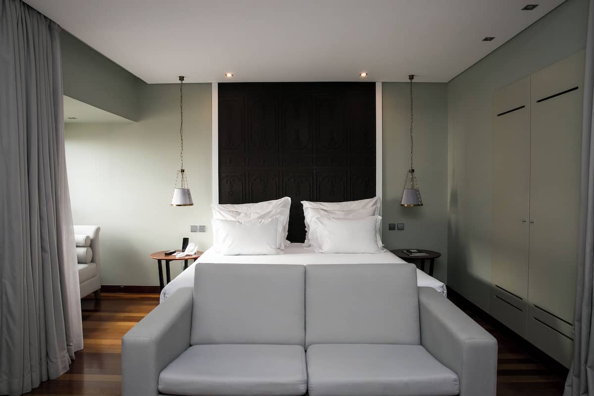 Una habitación de hotel moderna con una cama grande, un sofá y un armario.