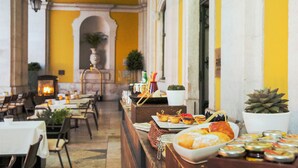 A restaurant with tables and chairs, a buffet with food items, and a fireplace in the background. - Pousada de Lisboa - Small Luxury Hotels Of The World (Lisbon)