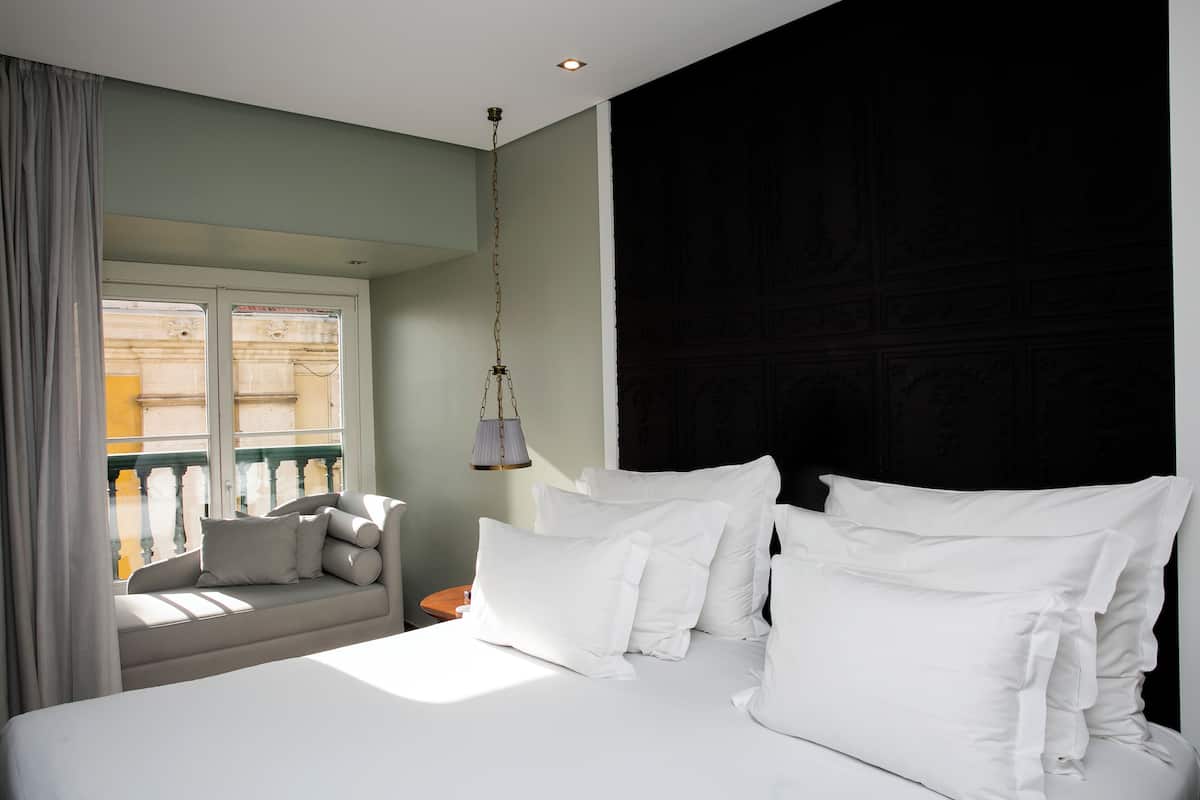 Un dormitorio con una cama grande, una lámpara colgante y vistas al balcón exterior.