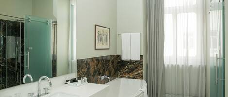 Un baño moderno con un espejo grande, un salpicadero de mármol, un lavabo doble y una bañera.